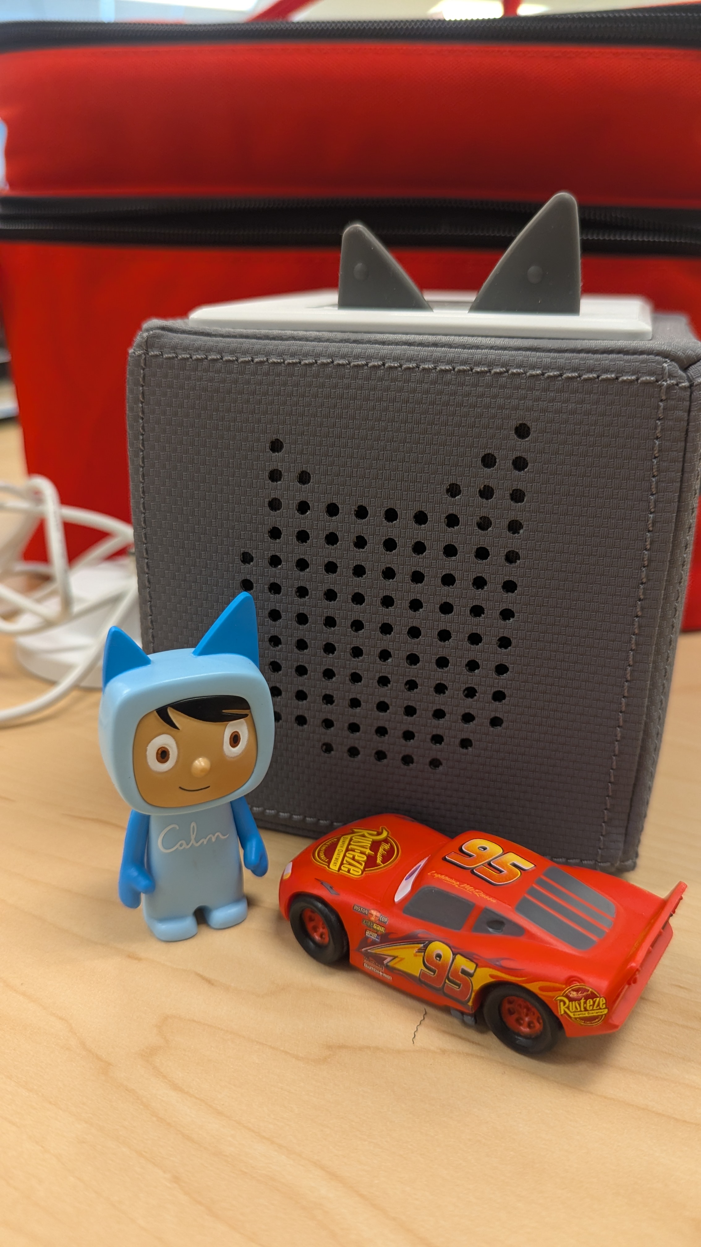 Grey TonieBox pictured with Lightning McQueen and "Calm" person Tonie Figurines in front. 