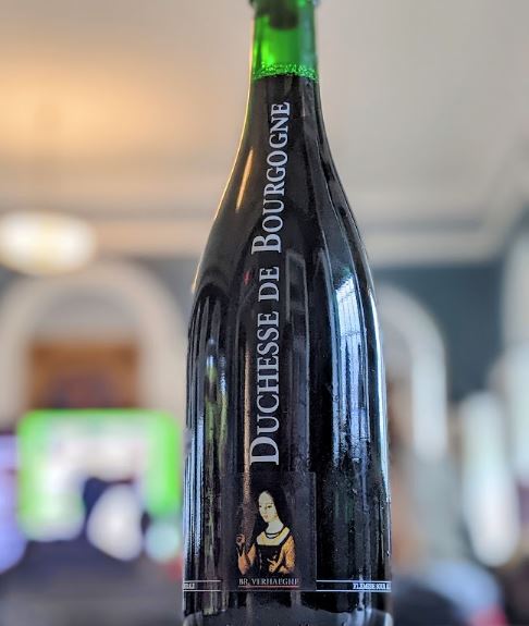 A Flanders Red style in a green bottle, on a table in the Community Room during Ale Together Now. 