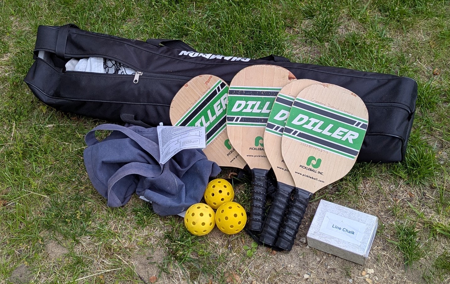 displays contents of portable pickleball kit: 4 paddles, balls, net in a bag, and line chalk
