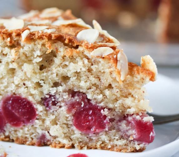 A slice of cherry almond cake on a white plate. 