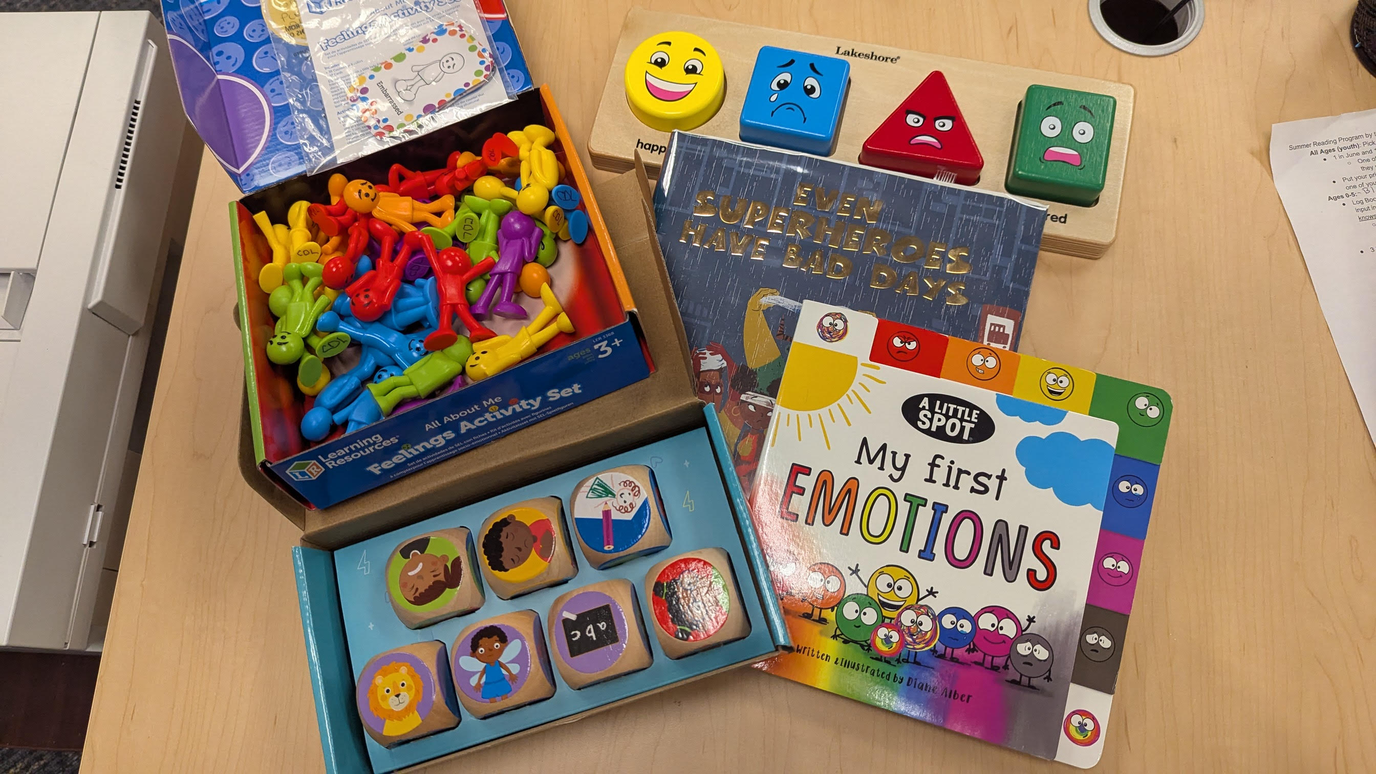 one emotions puzzle, one set of emotion action themed dice, one set of figurines and two books displayed