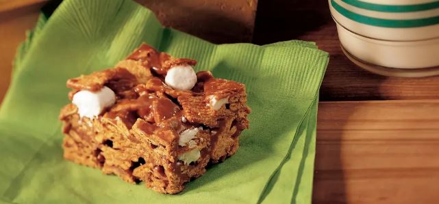 An indoor s'mores bar on a green napkin, on a wooden table. 