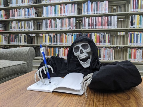 A skeleton writing a spooky story in the Library! 