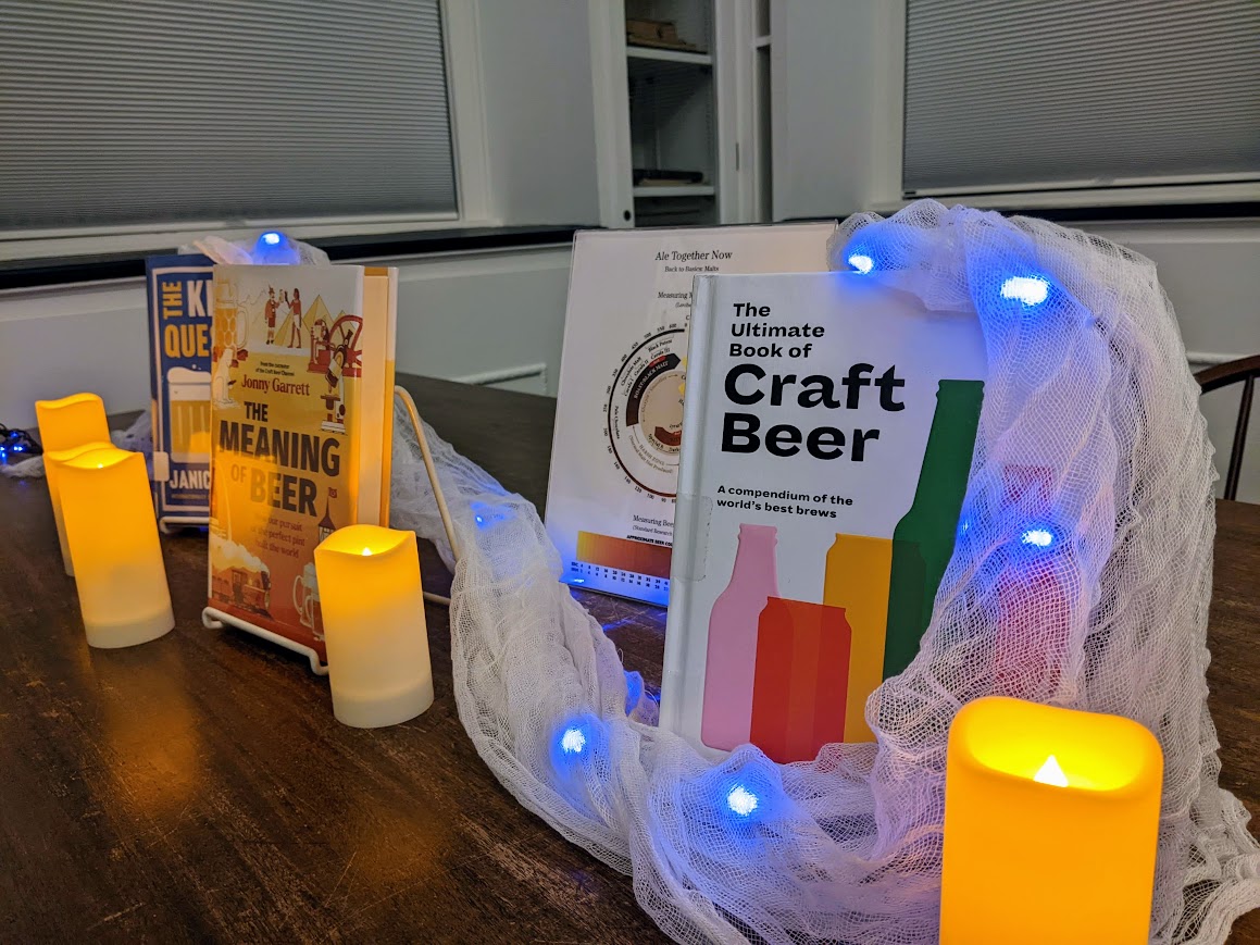 A variety of beer books surrounded by spooky lighting and candles in the Community Room. 
