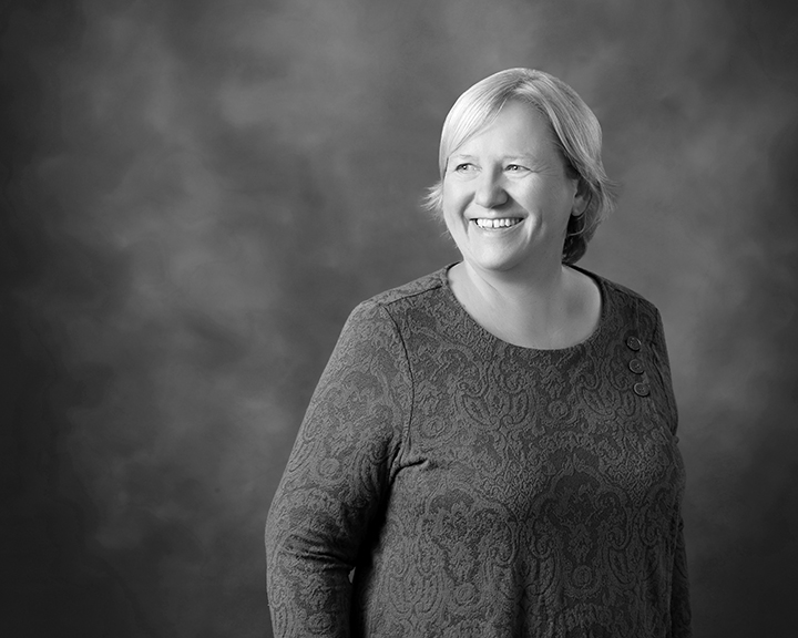 Black and white image of artist Gisela Bosch smiling on grey background.