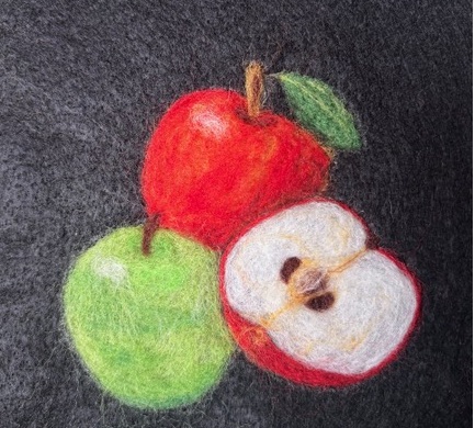 Needle felted wool in begins to take the shape of apples.