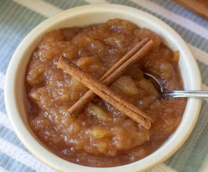 Applesauce in a bowl, with cinnamon sticks on top. 