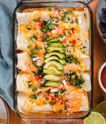 A glass dish filled with enchiladas, topped with sliced avocado. 