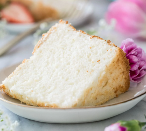 A slice of angel food cake on a plate with a purple flour. 