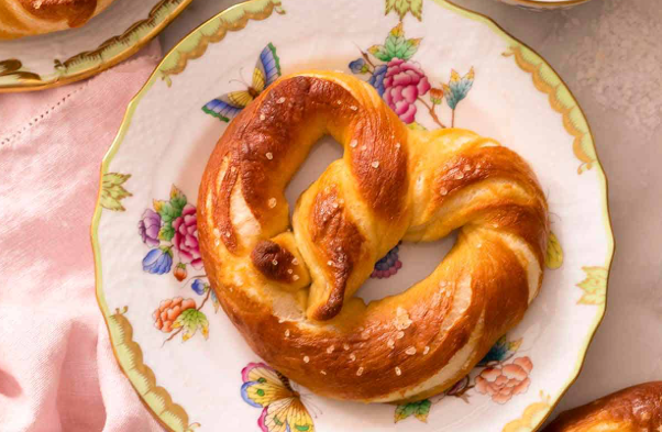 A soft pretzel on a floral plate. 