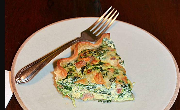A slice of quiche on a plate with a fork. 