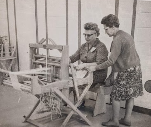 Two women weaving at a loom. 