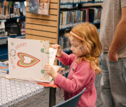 A child reading a picture book in the Youth department. 