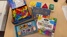 one emotions puzzle, one set of emotion action themed dice, one set of figurines and two books displayed