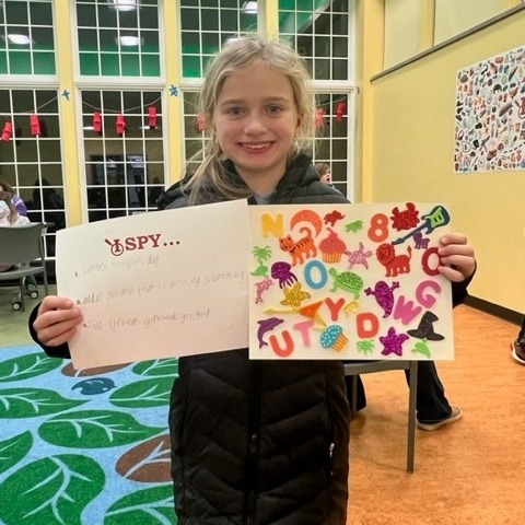 A young patron holding up an I Spy activity in the Youth Program Room. 