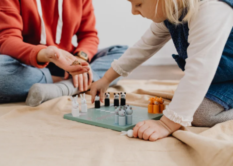 Two children sitting on the floor playing a board game. 