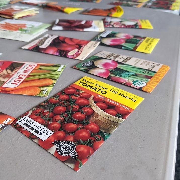 A variety of seed packets on a table in the Community Room. 