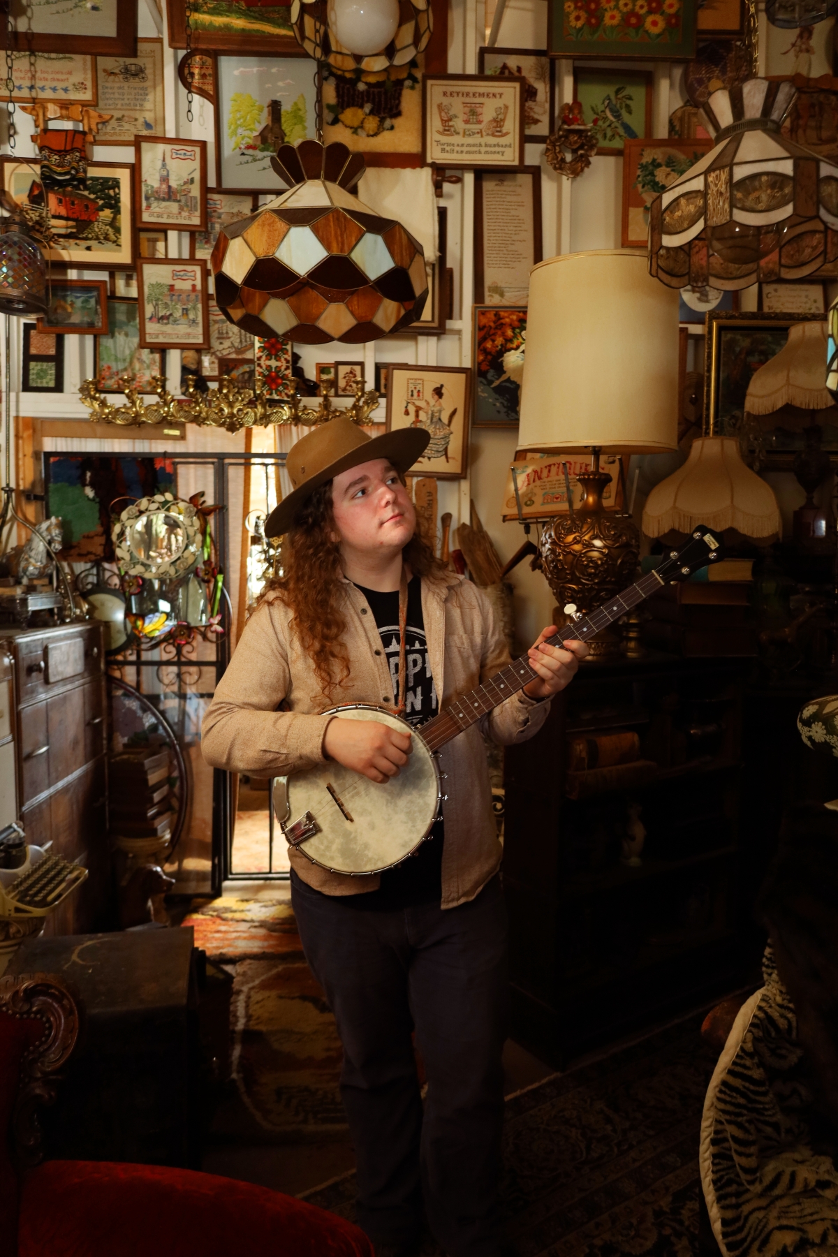 Sea Shanty educator Ben Traverse holds a banjo surrounded by antique items.