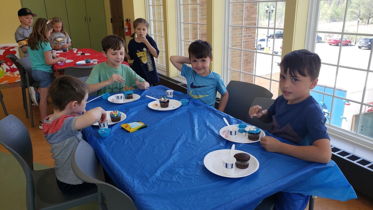 Kids in the Youth Program Room decorating cupcakes. 