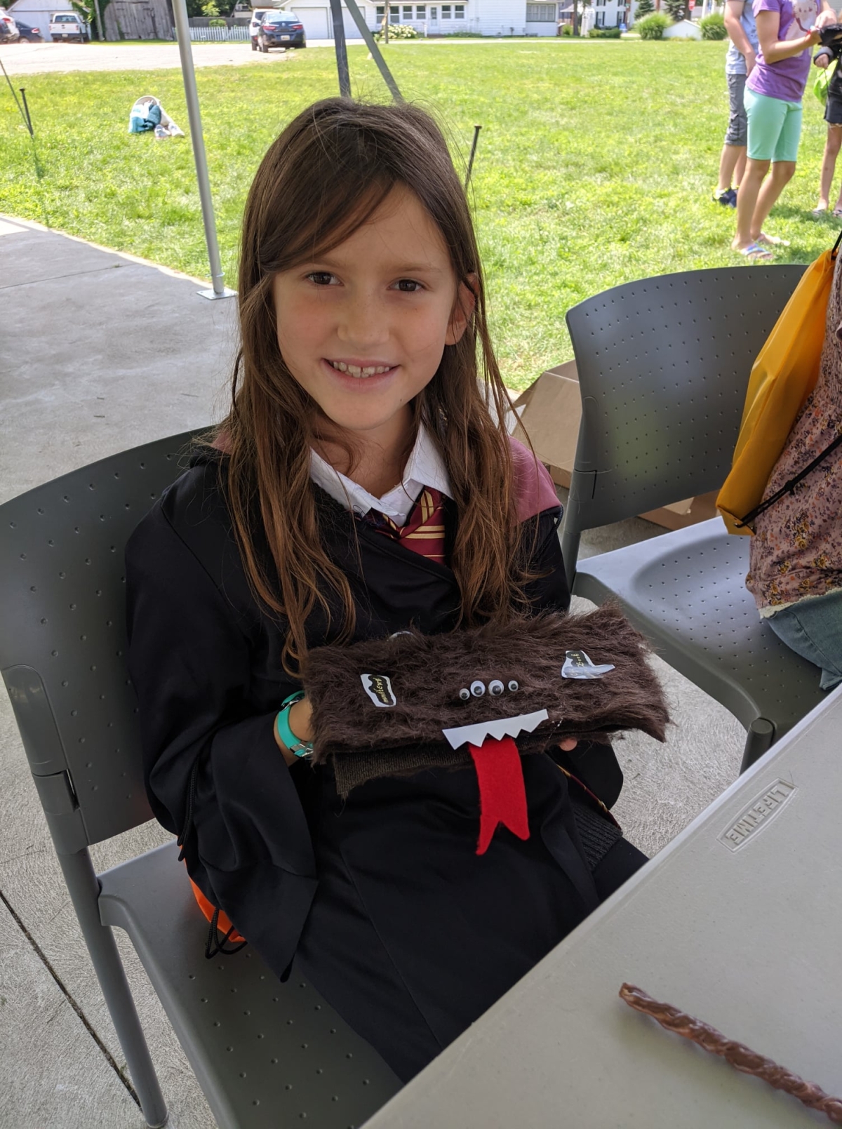 A girl holding up a Monster Book of Monsters outside the Library, as a part of Harry Potter Day! 
