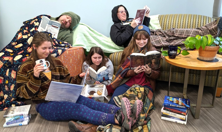 A group of Library staff, looking very cozy, reading together on various chairs. 