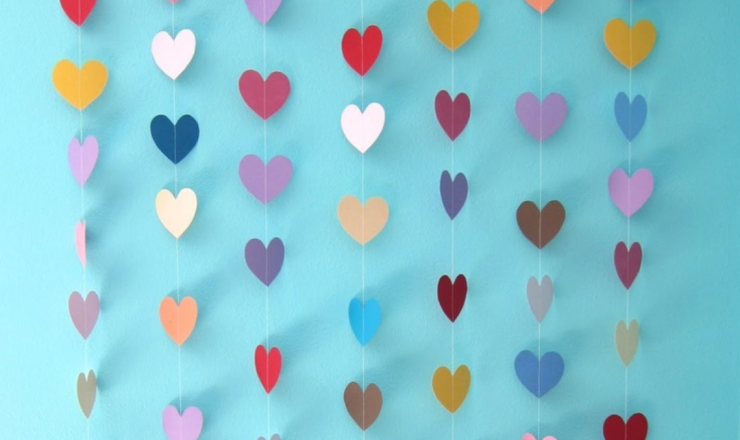 Paper hearts in various colors hanging on strings. 